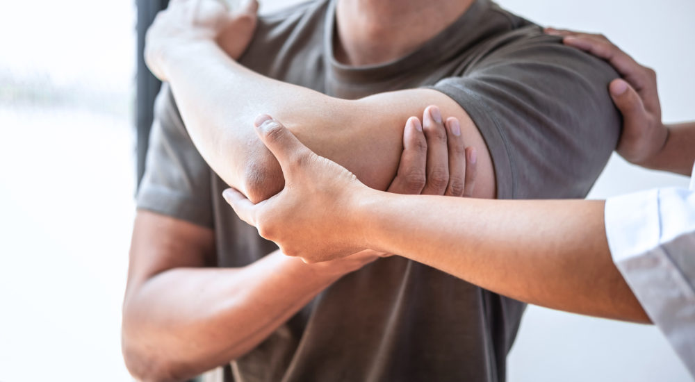 Female Physiotherapist working examining treating injured arm of Female Physiotherapist working examining treating injured arm of athlete male patient, stretching and exercise, Doing the Rehabilitation therapy pain in clinic.