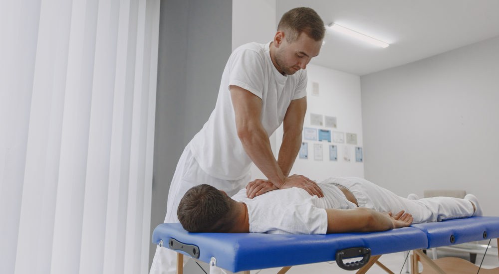 Male physiotherapist massaging man's back Man in the medical office. Physiotherapist is rehabilitating back.